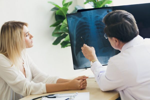 The doctor is describing the X-ray scan of the female patient’s The doctor is describing the X-ray scan of the female patient's chest.